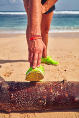 Sportsman stretching on a tropical sandy beach.