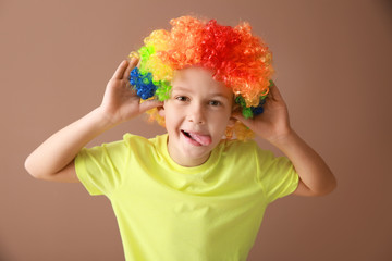 Little boy in funny disguise on color background. April fools' day celebration