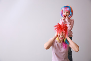 Funny girl with party whistle frightening mother on light background. April fools' day celebration