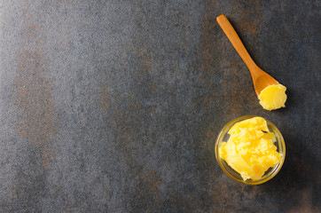 Top view of ghee butter and spoon with it on gray table, copy space
