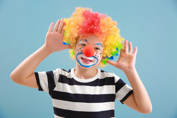 Cute little boy with clown makeup on color background. April fools' day celebration