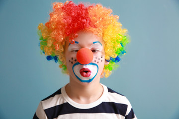 Cute little boy with clown makeup on color background. April fools' day celebration