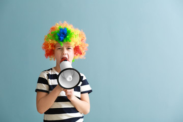 Obraz premium Little boy in funny disguise and with megaphone on color background. April fools' day celebration