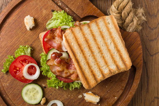 Toasted sandwich with bacon, tomato, cucumber and lettuce.