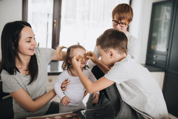 Fototapeta premium Family in pajamas. Brother and sister. New Year's mood. Nice view from the window. Kitchen interier. Ginger cookie. Fun photo.
