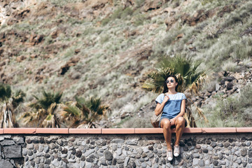 Naklejka na ściany i meble Happy pretty tourist brunette girl relaxing near rock.
