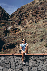 Happy pretty tourist brunette girl relaxing near rock.
