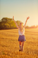 Young woman jumping and running in a wheat field.