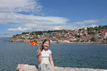 happy little girl waves with a Macedonian flag on lake Ohrid