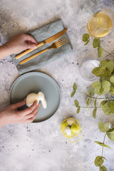 Happy Easter table setting:  mint green plate with  gold cutlery and  woman hands with bunny, painted Egg and wine. Scandinavian style  background with copy space