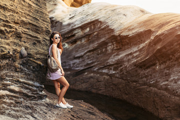 Pretty long hair brunette tourist girl relaxing on the stones near sea.