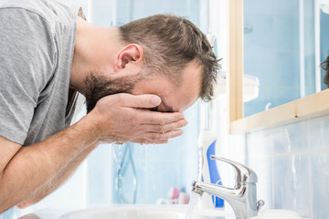 Man washing his face in bathroom