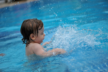 Fototapeta na wymiar Baby plays in a pool with his Mom
