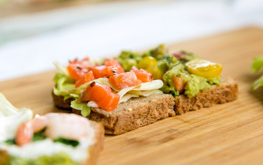 Open sandviches with guacamole, salmon and prawn on wood texture  background