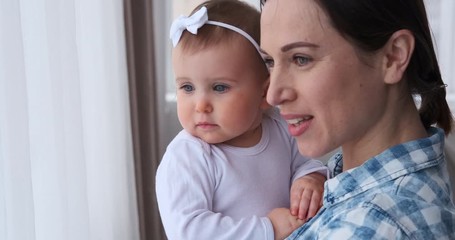 Mother talking with curious baby girl at home