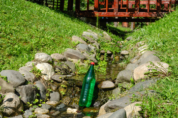 Green plastic bottle of mineral water in a stream