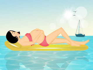 pregnant woman lying on the mat at the sea