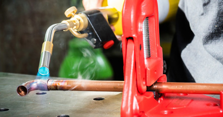  In the workshop, connecting copper pipes with a burner