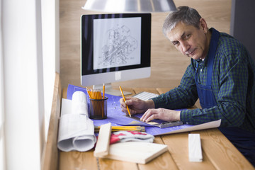 Fototapeta na wymiar Engineer carpenter working on laptop and sketching project