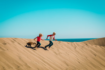 happy boy and girl play in sand dunes