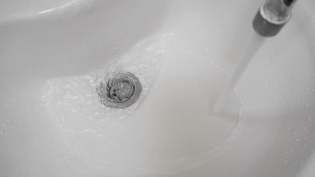Water flows from the faucet into the sink or wash basin in the bathroom