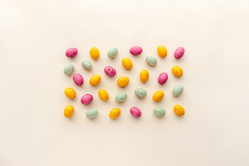 Fototapeta na wymiar Easter chocolate eggs candy on a pastel yellow background, creative flat lay easter concept, top view