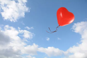Photo sur Plexiglas Ballon red heart shaped balloon flies into the blue sky with clouds, love concept, copy space
