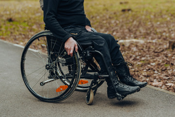 Close-up of male hand on wheel of wheelchair during walk in park
