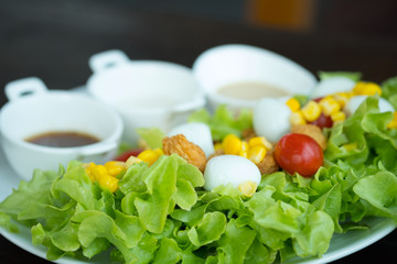 Fresh salad with green oak lettuce, corn, tomato, fried chicken and quail eggs