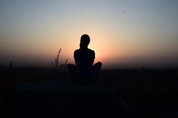 silhouette of a women meditating on the hill at sunrise