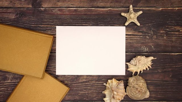 White paper for writing and shells and books on wooden background - Stop motion