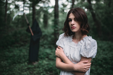 Young female victim in white dress in the forest
