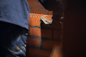 Fototapeta premium professional construction worker laying bricks and building barbecue in industrial site. Detail of hand adjusting