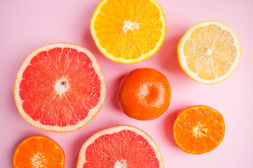 Naklejka na ściany i meble Flat lay of cut ripe juicy citrus fruits on pink background. Citrus pattern.