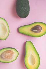 Ripe organic avocados with seed, avocado half and whole fruit on pink background.