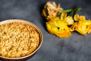Yellow flower, cookies and apple pie lying on gray background