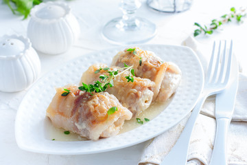 Chicken rolls with bacon and cheese on a white table, horizontal