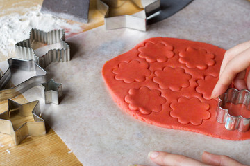 woman  hand cutting red dough in the shape of flowers