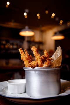 Golden crisp fried crumbed chicken nuggets served in a metal dish as an appetizer or finger food on bar background