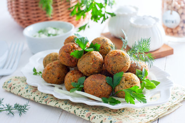 Chickpea falafel with fresh herbs on a white table, horizontal