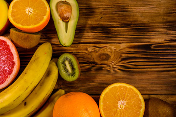 Still life with exotic fruits. Bananas, mango, oranges, avocado, grapefruit and kiwi fruits on wooden table. Top view