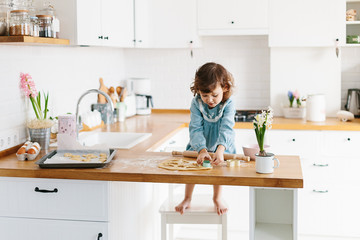 Little girl preparing easter cookies at the kitchen.