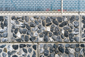 detail background of rock wall granite texture background with tile and grout joints and a fence on top