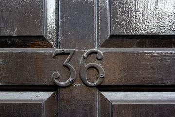 House number 36 with the thirty six in black metal lettering on a black painted wooden door