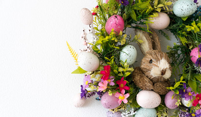 easter wreath with colorful eggs and flowers and a rabbit in the center
