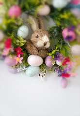 easter wreath with colorful eggs and flowers and a rabbit in the center