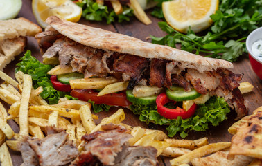Gyros, shawarma, take away, street food.  Sandwich with meat on wooden table