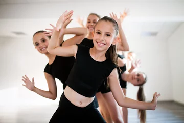 Rollo Gruppe fitter glücklicher Kinder, die zusammen Tanzen und Ballett im Studio trainieren © NDABCREATIVITY
