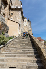 Fototapeta na wymiar People on steep steps Big stairs at Pilgrimage town of Rocamadour, Episcopal city and sanctuary of the Blessed Virgin Mary, Lot, Midi-Pyrenees, France