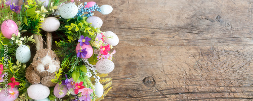 easter wreath with colorful eggs and flowers and a rabbit in the center